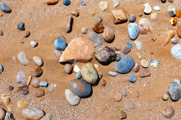 Fototapeta na wymiar Sandy beach with the multicolor pebbles on the african Atlantic ocean coast.