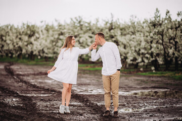 Happy family couple in the spring blooming apple orchard. Young couple in love enjoy each other...