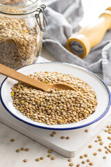 Uncooked brown lentils. Raw legume in bowl on kitchen table.