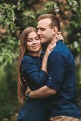 Fototapeta premium Handsome young guy with a girl stand in the spring garden. Romantic couple are walking in the park. Happy relationship concept