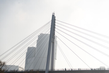 Fototapeta premium bridge over the river in the fog. People walk on a suspension bridge