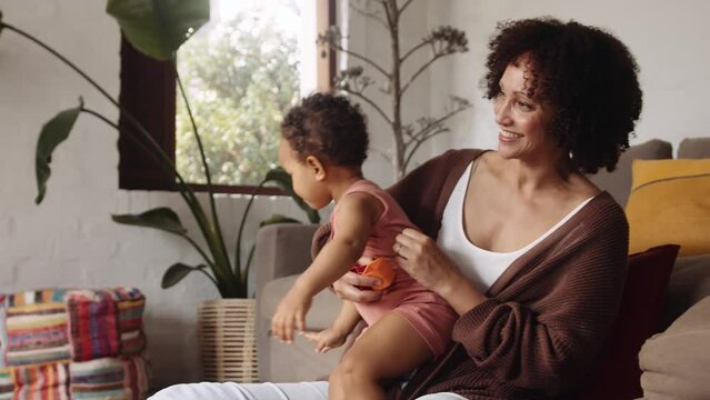 Biracial female and young child playing together in modern-styled living room in the daytime