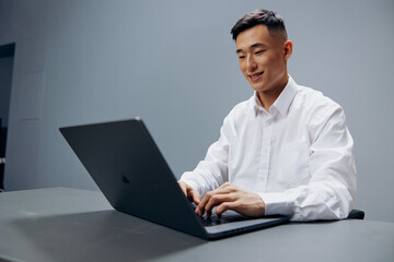 manager sits at a desk in front of a laptop Gray background