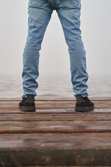 Strong against depression. Male legs standing defiant over immense ocean