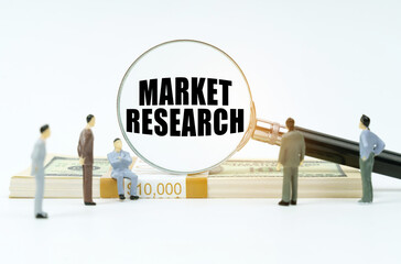 On a white surface, a dollar, figurines of people and a magnifying glass with the inscription - Market Research