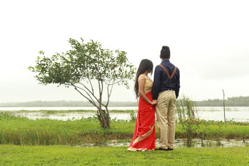 The handsome young man looks at his lover. There is also a small green tree near a beautiful lake