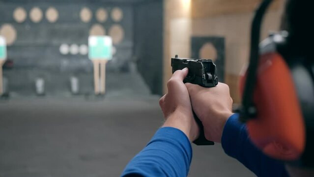 Shooting gallery. A young man shooting with a firearms. A smoking gun