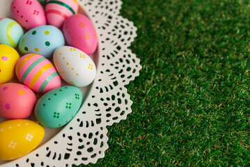Easter background with colorful painted pink, blue, yellow Easter eggs and green grass. Top view with copy space. Easter holidays banner and header.