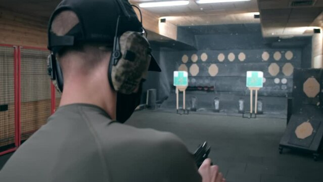 Shooting gallery. A young man shooting with a firearms. A smoking gun