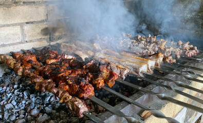 Pork and lamb shashlik in metal skewers on a stone grill