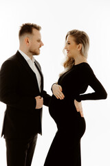  portrait of a couple, pregnant woman with her husband dressed in black on a white background.