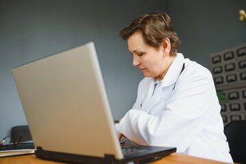 pretty female middle aged medical worker with x-ray standing by window