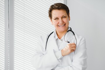 Portrait of middle age female doctor is wearing a white doctor's coat with a stethoscope around her neck.