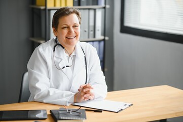 Portrait of middle age female doctor is wearing a white doctor's coat with a stethoscope around her neck.