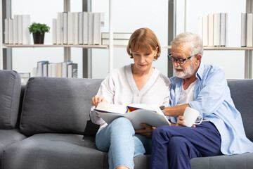 senior couple reading a book and self learning in living room