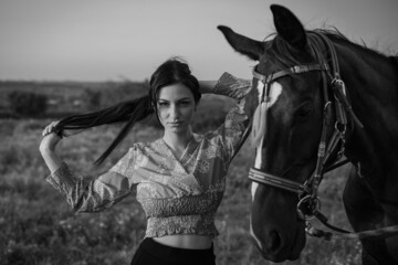 Obraz premium Girl with long black hair in the countryside. Ipadrome with horses. Rural landscapes, wild west.