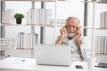 senior businessman using laptop computer and headache from work