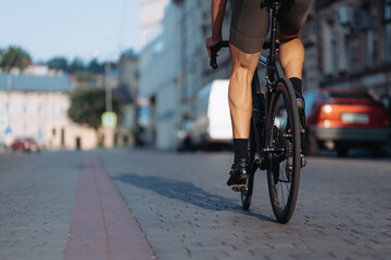 Fototapeta na wymiar Close up of man with muscular legs riding bike on street