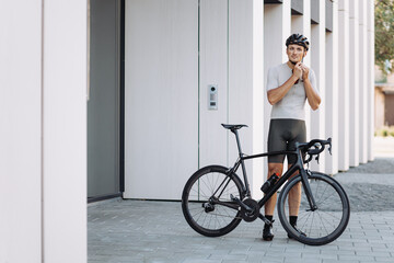 Man standing near black bike and wearing safety helmet