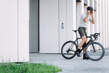 Cyclist putting on sport glasses while sitting on bike