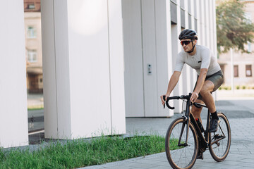 Active sportsman in helmet riding bike on city streets