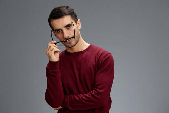 handsome man with glasses posing gesture with hands red sweater Gray background