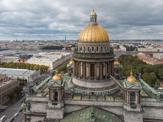 Naklejka premium Cropped aerial photo of Saint Isaacs Cathedral in Saint Petersburg. Large orthodox church with golden dome and colonnade. Travel destination. Cloudy sky. Vacation concept.