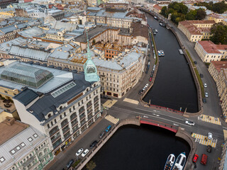 Fototapeta premium Aerial photo of Red bridge over Moyka river in Saint Petersburg, Russia. Au Pont Rouge store. Old residential buildings with rusty rooftops. Travel destination.