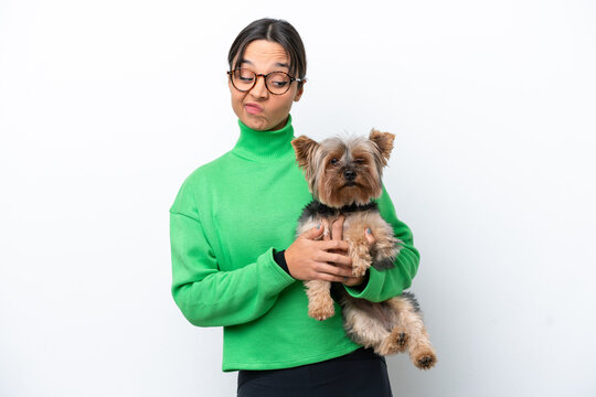 Young hispanic woman holding a dog isolated on white background with sad expression