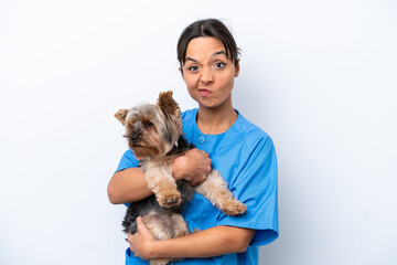 Young veterinarian woman with dog isolated on white background making doubts gesture while lifting...