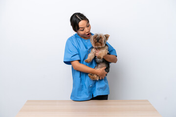 Obraz premium Young veterinarian woman with dog on a table isolated on white background with surprise and shocked facial expression