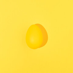 Yellow Easter egg isolated on yellow background. Minimal food concept. Monochromatic composition.