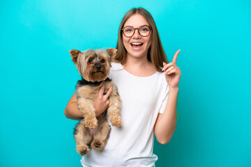 Young Lithuanian woman holding a dog isolated on blue background pointing up a great idea