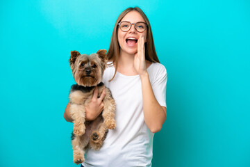 Obraz premium Young Lithuanian woman holding a dog isolated on blue background shouting with mouth wide open