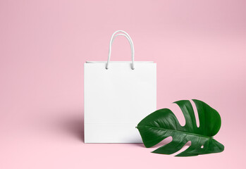 white gift bag on a pink background with a palm leaf. Advertising package for the logo. Branding.