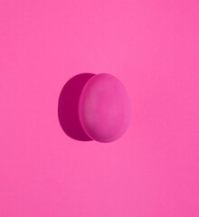 Pink Easter egg isolated on pink background. Minimal holiday concept. Monochromatic composition. Happy Easter card.
