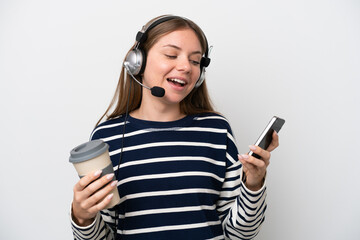 Telemarketer caucasian woman working with a headset isolated on white background holding coffee to take away and a mobile