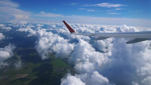 View from the window of the aircraft on the wing and beautiful cumulus clouds high above the ground