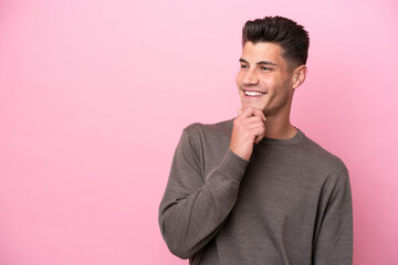 Young caucasian man isolated on pink background looking to the side and smiling