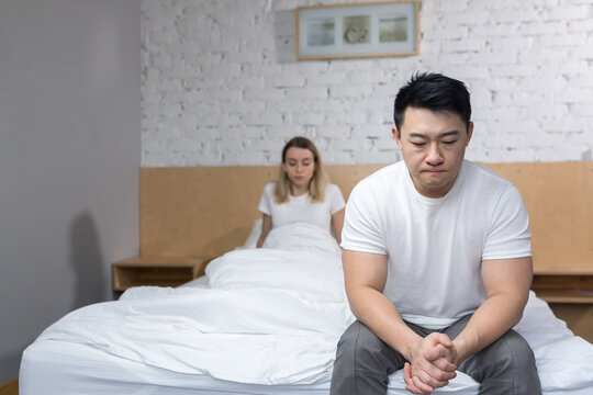 Frustrated Asian sitting on the edge of the bed, family disappointed and quarreling in bed, unhappy family at home