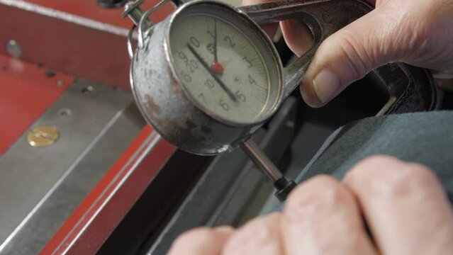 Tailor measures black leather slice width with special tool over aligning workbench closeup. Concept entry system case craft
