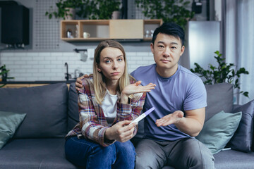 Young couple at home frustrated showing negative doctor pregnancy test, online doctor consultation, man and woman together at home trying to get pregnant