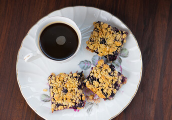 blueberry crumb bars on antique plate with cup of coffee. 