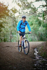Obraz premium Keeping fit and enjoying nature. Shot of a male cyclist riding along a mountain bike trail.