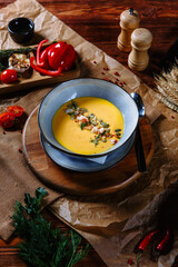 Yellow pumpkin soup in a clay plate on the table.