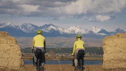 The man and woman travel on mixed terrain cycle bike touring with bikepacking. The two people...