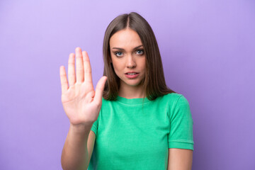 Young caucasian woman isolated on purple background making stop gesture