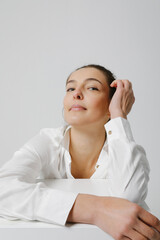 Joyful woman dressed in casual shirt, posing over white wall. Vertical.
