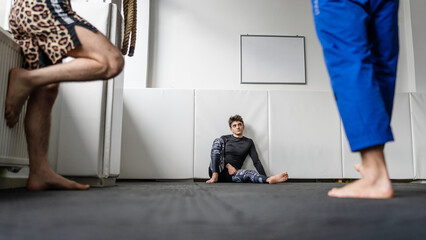 One man brazilin jiu jitsu bjj athlete at training taking a brake rest on the tatami mats sitting