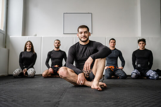 Front view of the main instructor professor at the brazilian jiu jitsu bjj grappling academy sitting on the tatami mats in front of his students